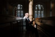 Man in Black Suit Jacket Sitting on Brown Wooden Bench