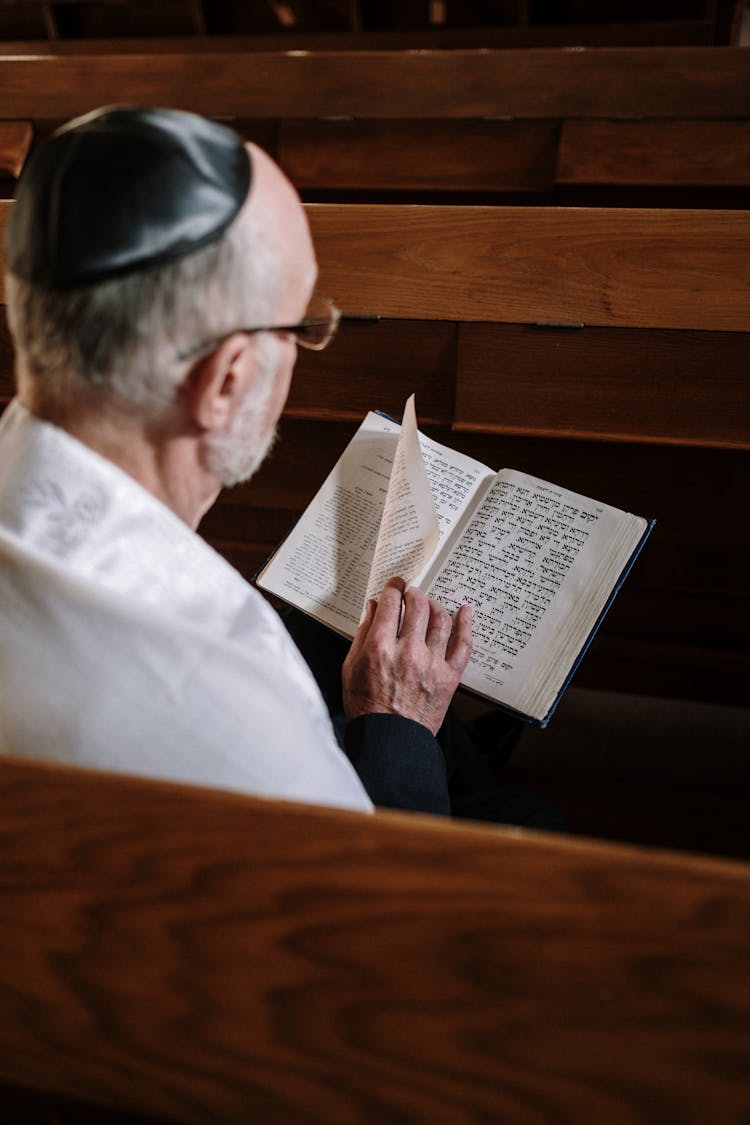 A Man In A Kippah And Tallit Reading A Chumash