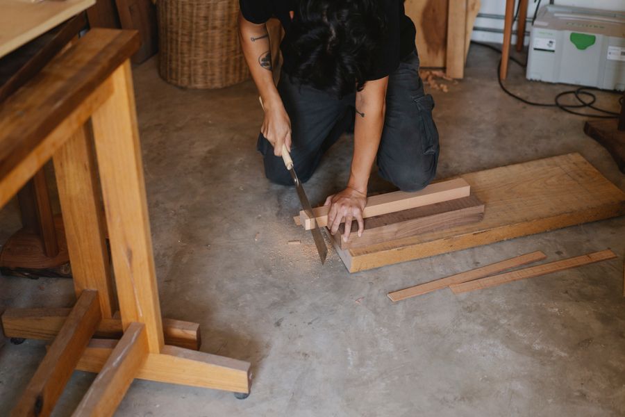 Werkzeuge mit H – Handwerker schneidet Holz mit Handsäge in der Werkstatt