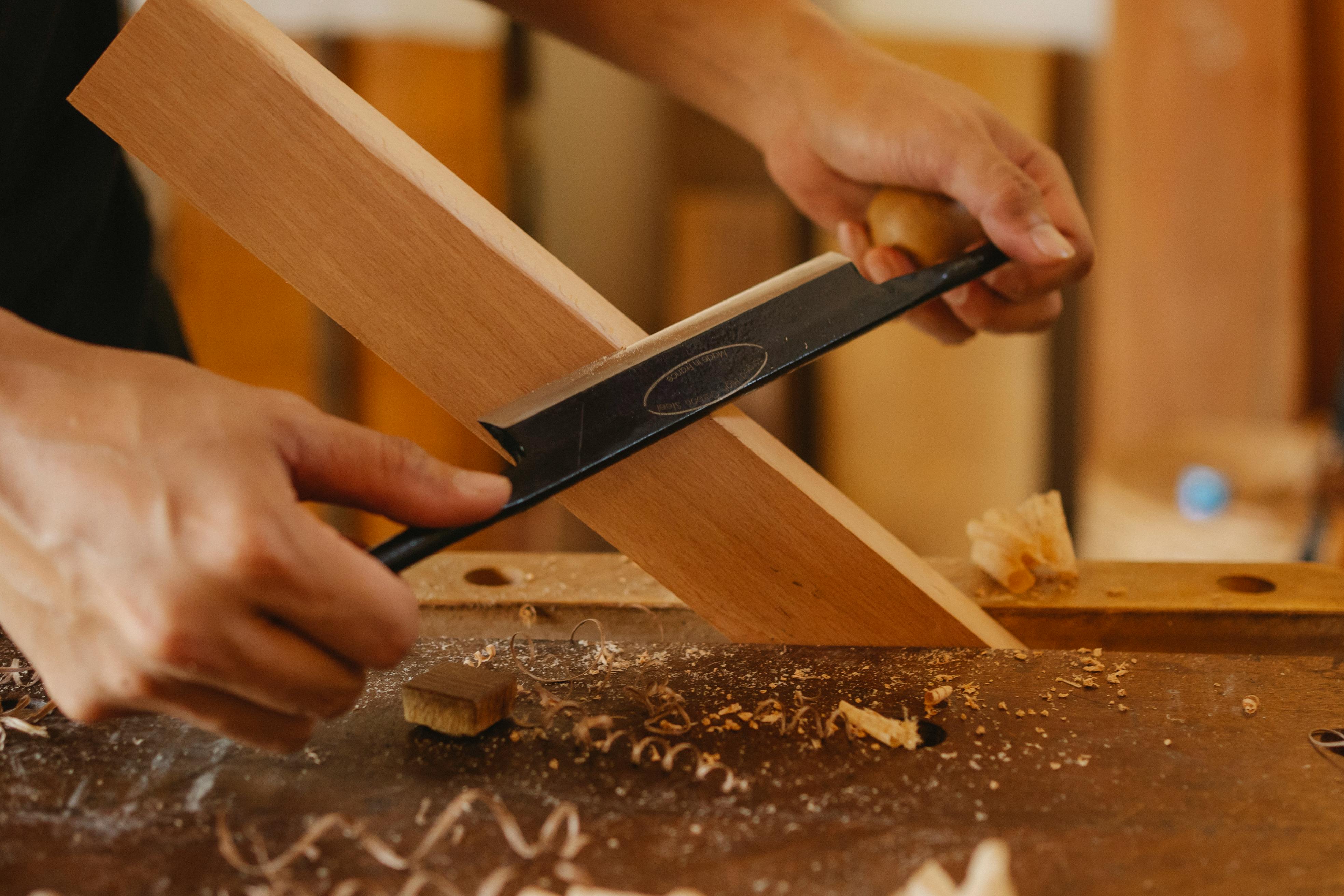 male artisan shaping plank with drawknife