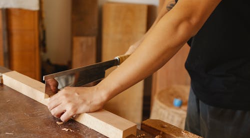 Free Professional woodworker cutting wood with hacksaw Stock Photo
