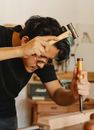 Artisan shaping wooden plank with hammer and chisel