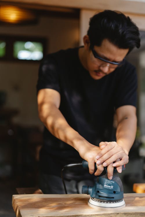 Artisan polishing timber board with instrument in workshop