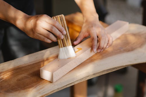 Craftsman smearing wooden plank with oil