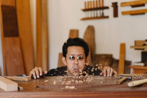 Free Asian carpenter in sunglasses preparing table for making woodwork in joinery workshop with manual instruments Stock Photo