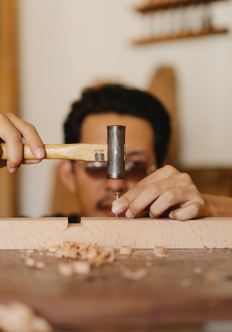 Carpenter Hammering Nail In Workshop