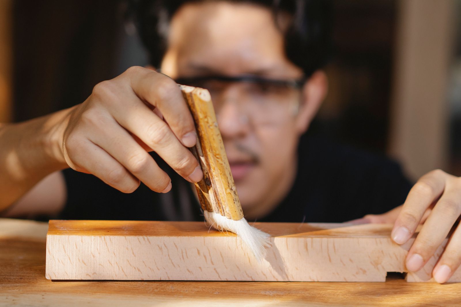 Artisan applying varnish to wooden surface in a workshop, evoking the monthly oiling rhythm
