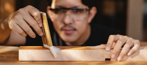 Professional artisan varnishing wooden detail in workplace