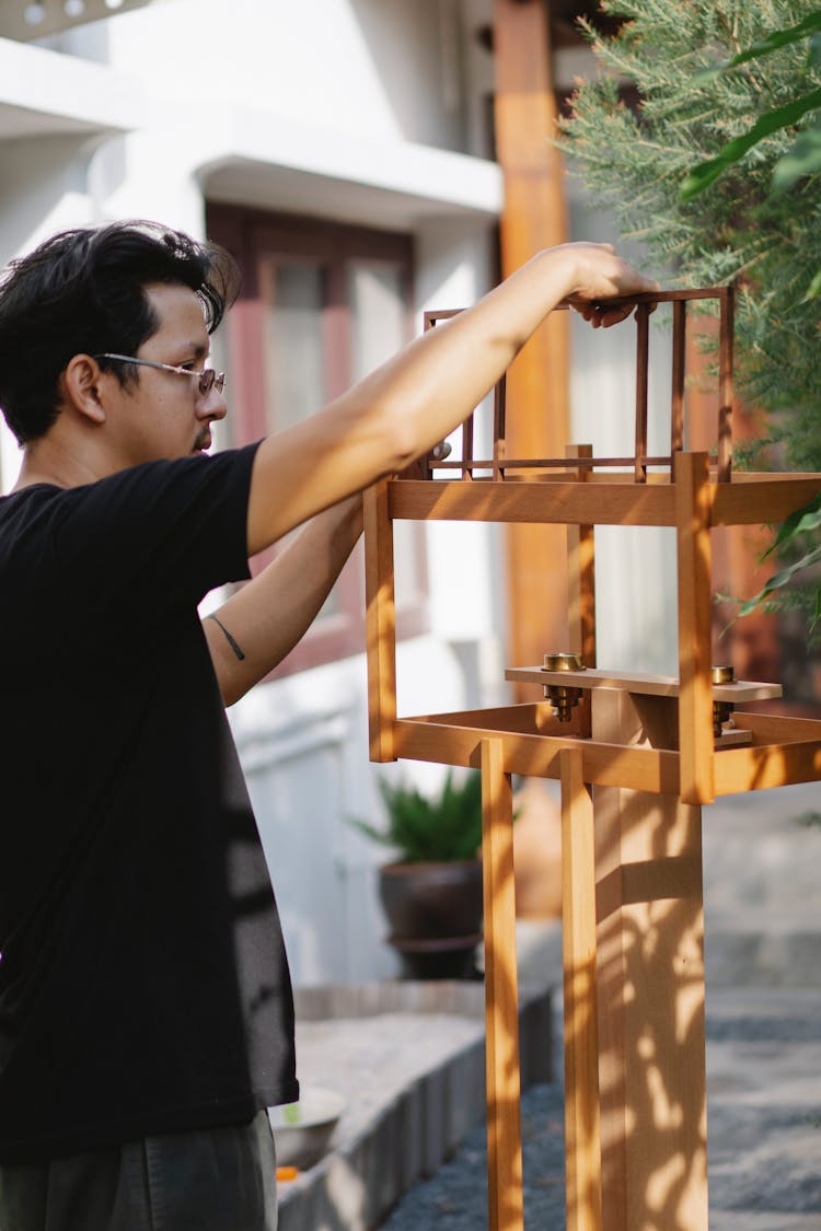 Young Man With Wooden Birds House In Garden