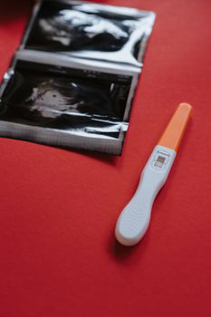 特写镜头下的验孕棒和超声图像置于红色背景上，突出显示检测结果