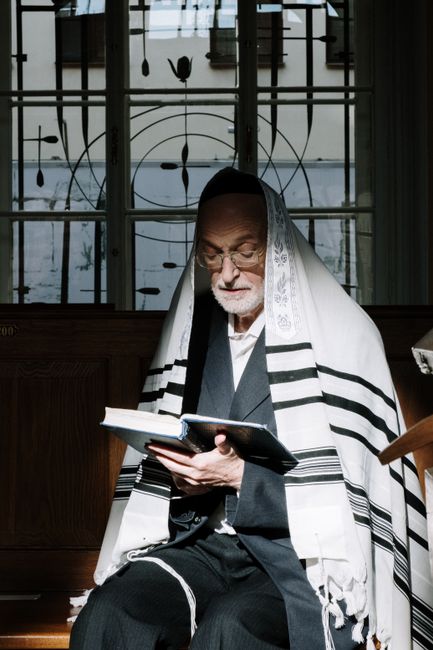 Elderly man reading a religious text in a peaceful indoor setting.