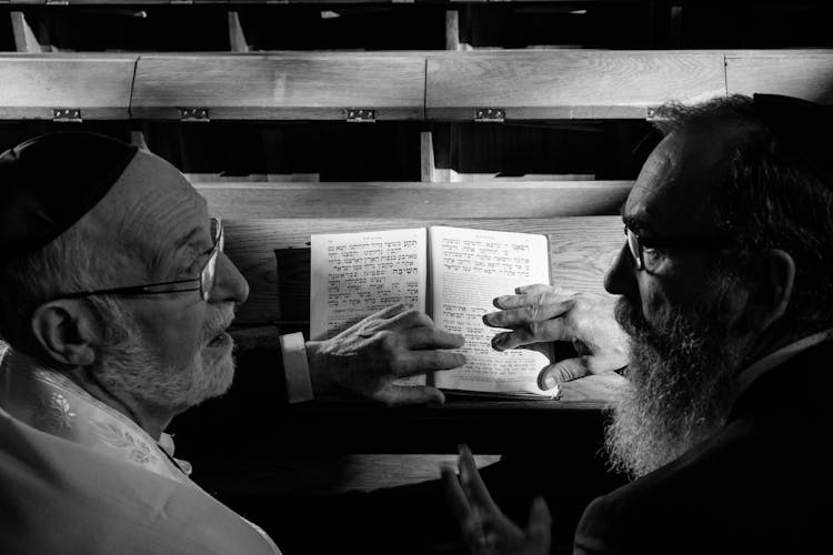 Grayscale Photography Of Two Men Holding A Book