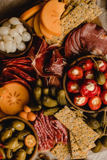 Charcuterie board with cured meats, cheeses, tomatoes, and bread`