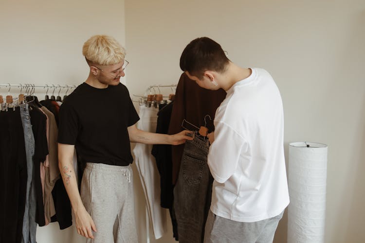 Two Men Holding Clothes On Clothes Hangers