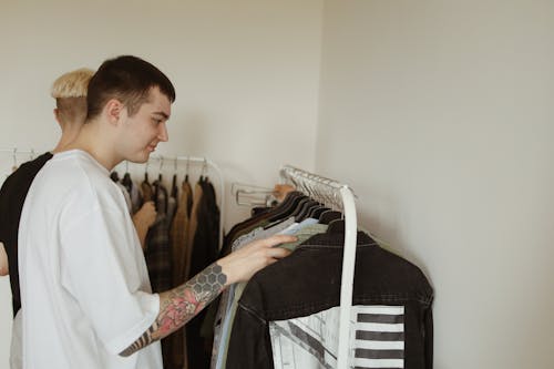 Man in White Shirt Checking Clothes Haning on a Clothes Rack