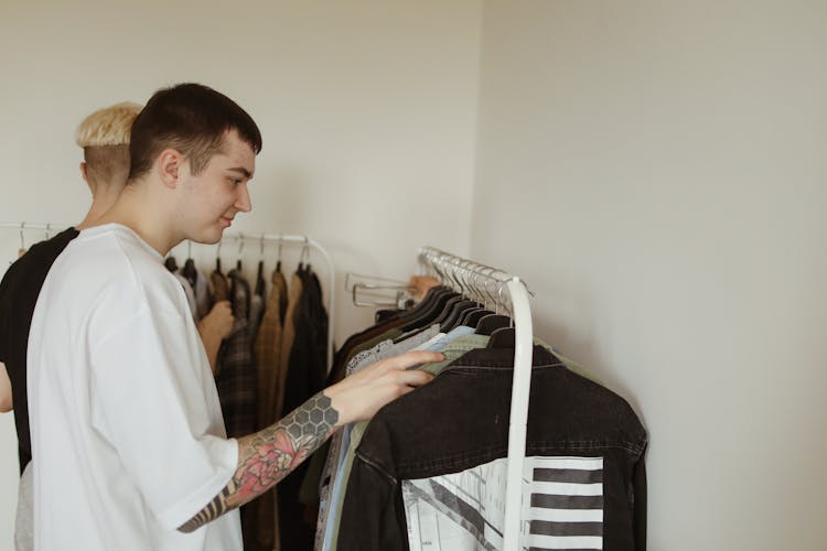 Man In White Shirt Checking Clothes Haning On A Clothes Rack