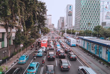 A bustling city street filled with cars and buses during the day.