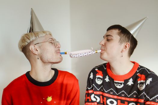 在热闹的新年庆祝活动中，两个成年人在室内穿着节日服装和派对帽