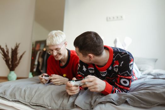 两个快乐的男人在舒适的卧室里一起玩电子游戏，享受着爱与放松