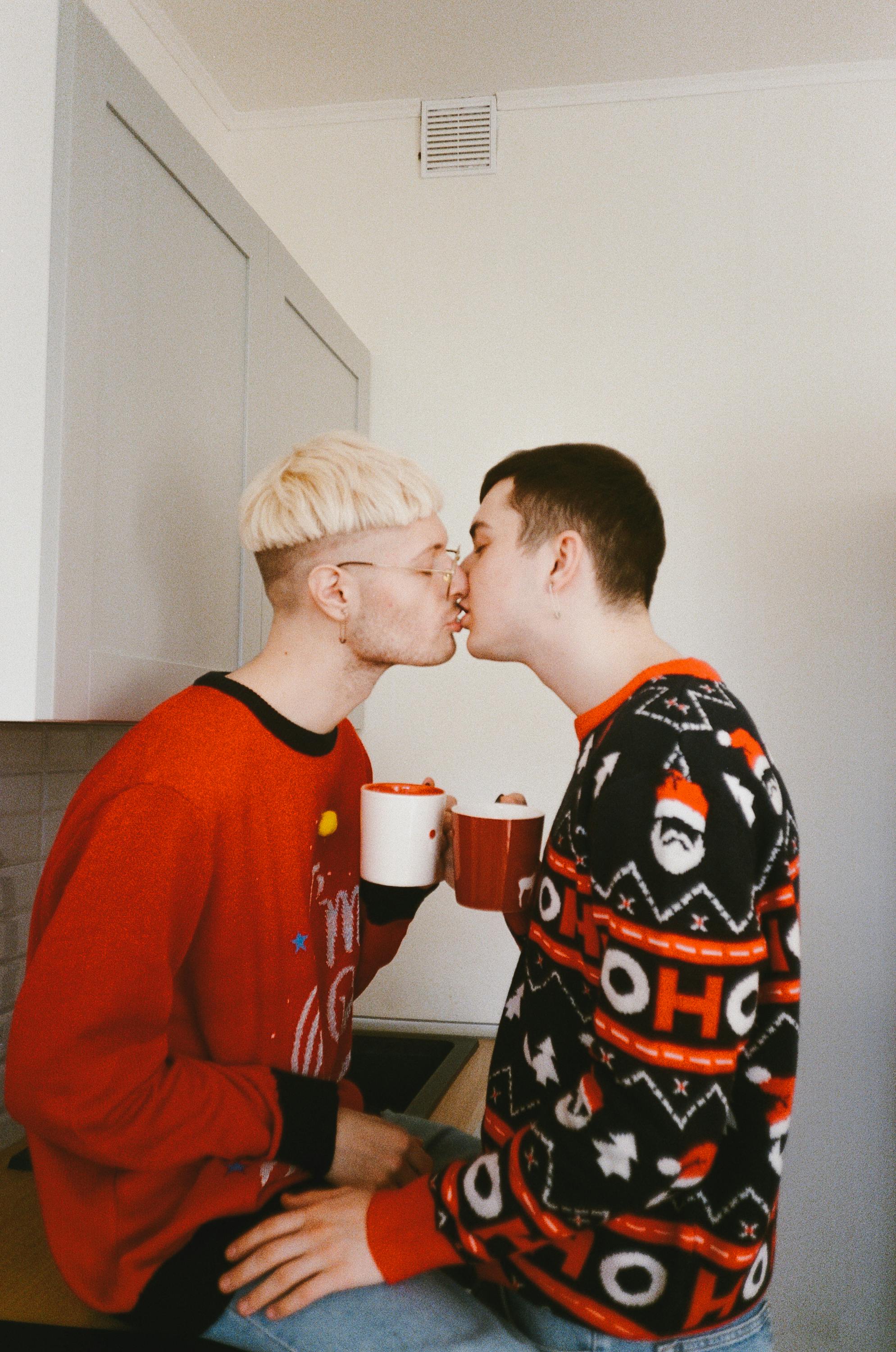 couple in christmas sweaters kissing in the kitchen