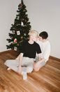 一对夫妇在圣诞树旁共享亲密时刻，体现了爱与团结