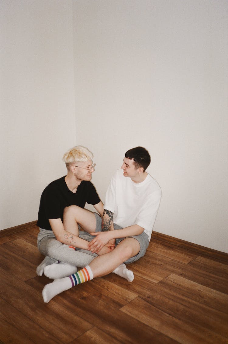 Two Men Sitting On The Floor While Talking Together