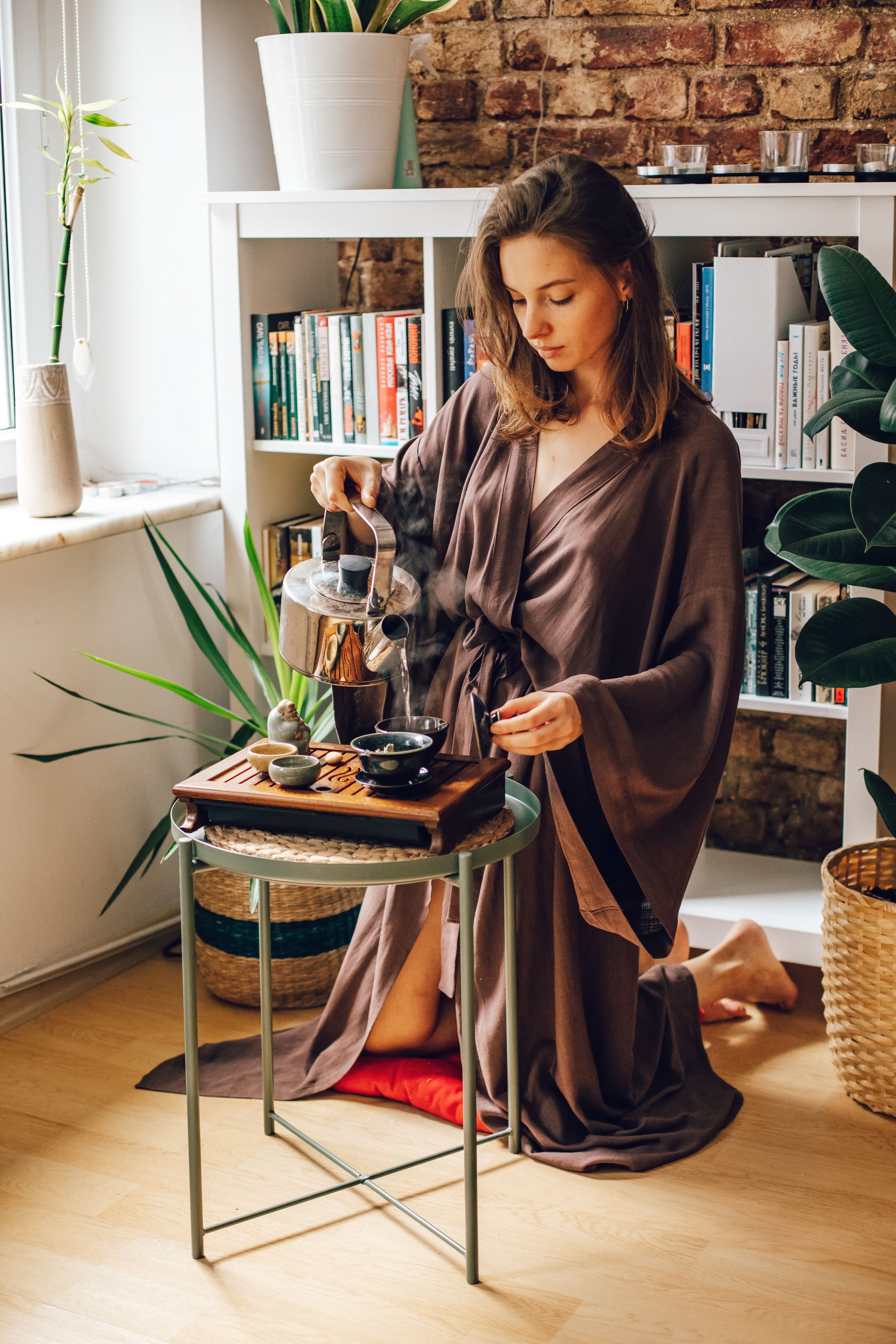 Uma mulher em um robe aconchegante serve chá em um ambiente doméstico acolhedor.