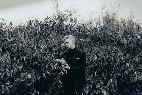 Grayscale Photo of a Man in Black Blazer Holding a Bird 