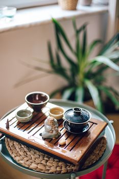 A peaceful tea arrangement with a Buddha figurine and bowls on a tray, set on a wooden coffee table.