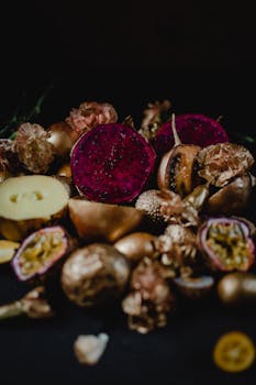 Moody dark food photography featuring fresh dragon fruit, passion fruit, and flowers.