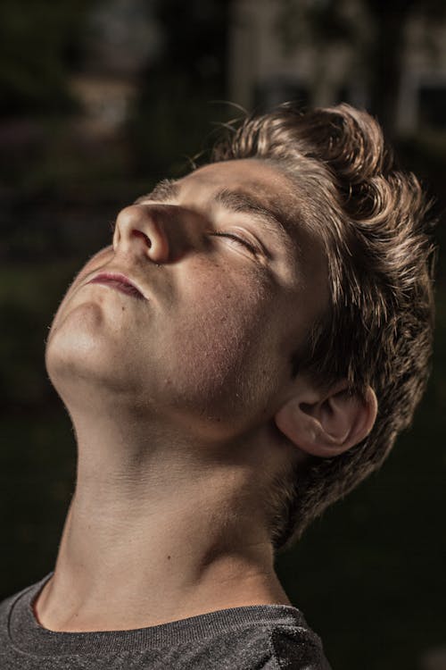 Young handsome serious blond man sitting with closed eyes on blurred background