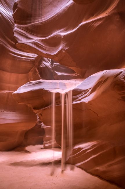 Marvel at the mesmerizing sandfall within the stunning geological formations of Antelope Canyon, Arizona.