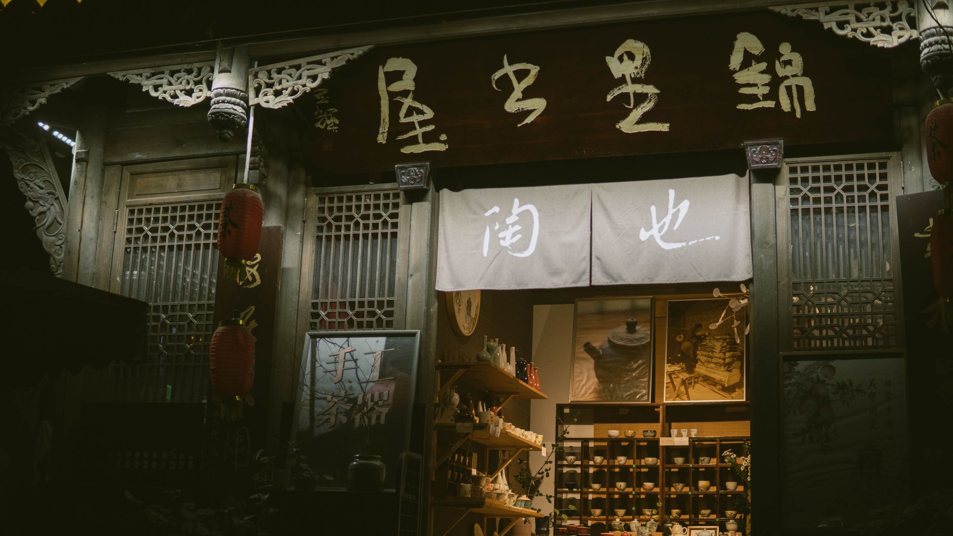 A beautifully illuminated traditional tea shop entrance with Chinese characters and decor, captured at night.