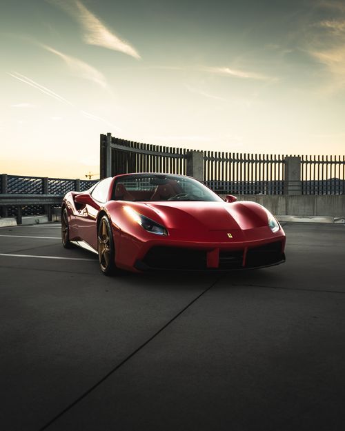 Free New expensive shiny red automobile parked on asphalt street under bright cloudy sky Stock Photo