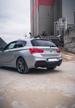 Elegant silver car parked in an industrial area, showcasing luxury and style.