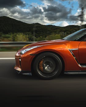Modern automobile with glossy headlights and low sport bumper on asphalt road against mountains with lush vegetation