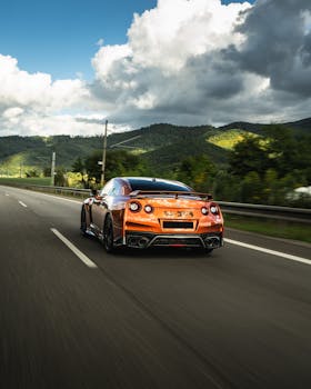 A sleek luxury sports car speeds on an open highway through beautiful countryside.
