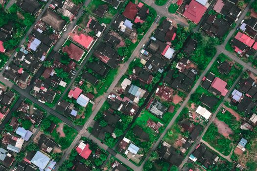 Aerial view of infrastructure of tropical countryside with residential cottages and green trees in daytime
