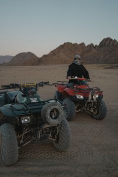 黎明时分，全地形车骑手探索广阔沙漠地形的动作镜头充满活力