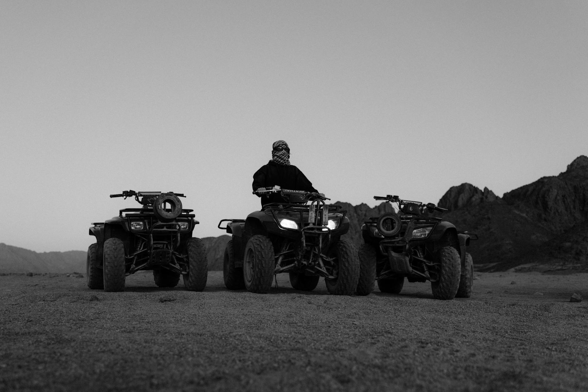 Grayscale Photo of Man Riding Atv