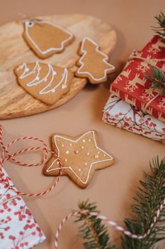 Christmas gingerbread cookies and wrapped gifts on a wooden tray with festive decorations.