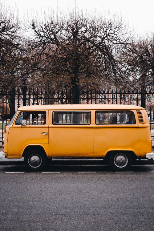 Free Captivating vintage yellow Volkswagen bus parked by bare trees in Paris. Stock Photo