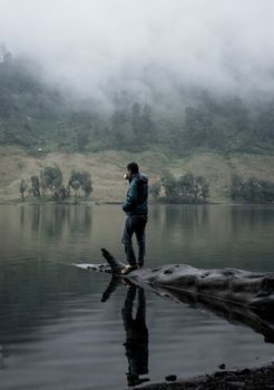 在印度尼西亚东爪哇省，一名男子站在雾气缭绕的湖边，感受着大自然的宁静