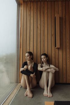 两个女人坐在现代木制内饰的大窗户旁，散发着平静和放松的气息