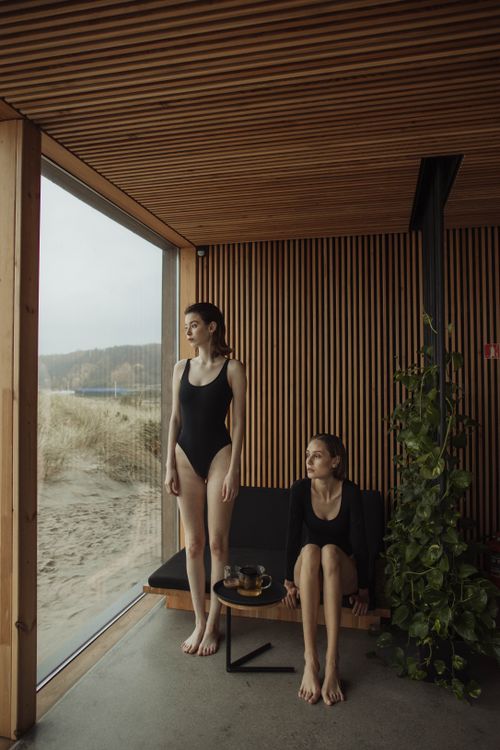Free Two women relaxing at a modern indoor beachside spa retreat, enjoying serene views. Stock Photo