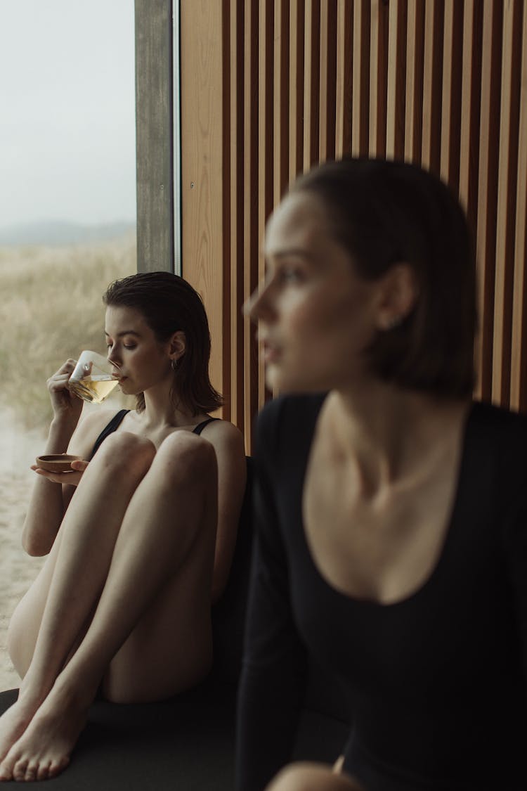 Women Sipping Tea By The Glass Wall 