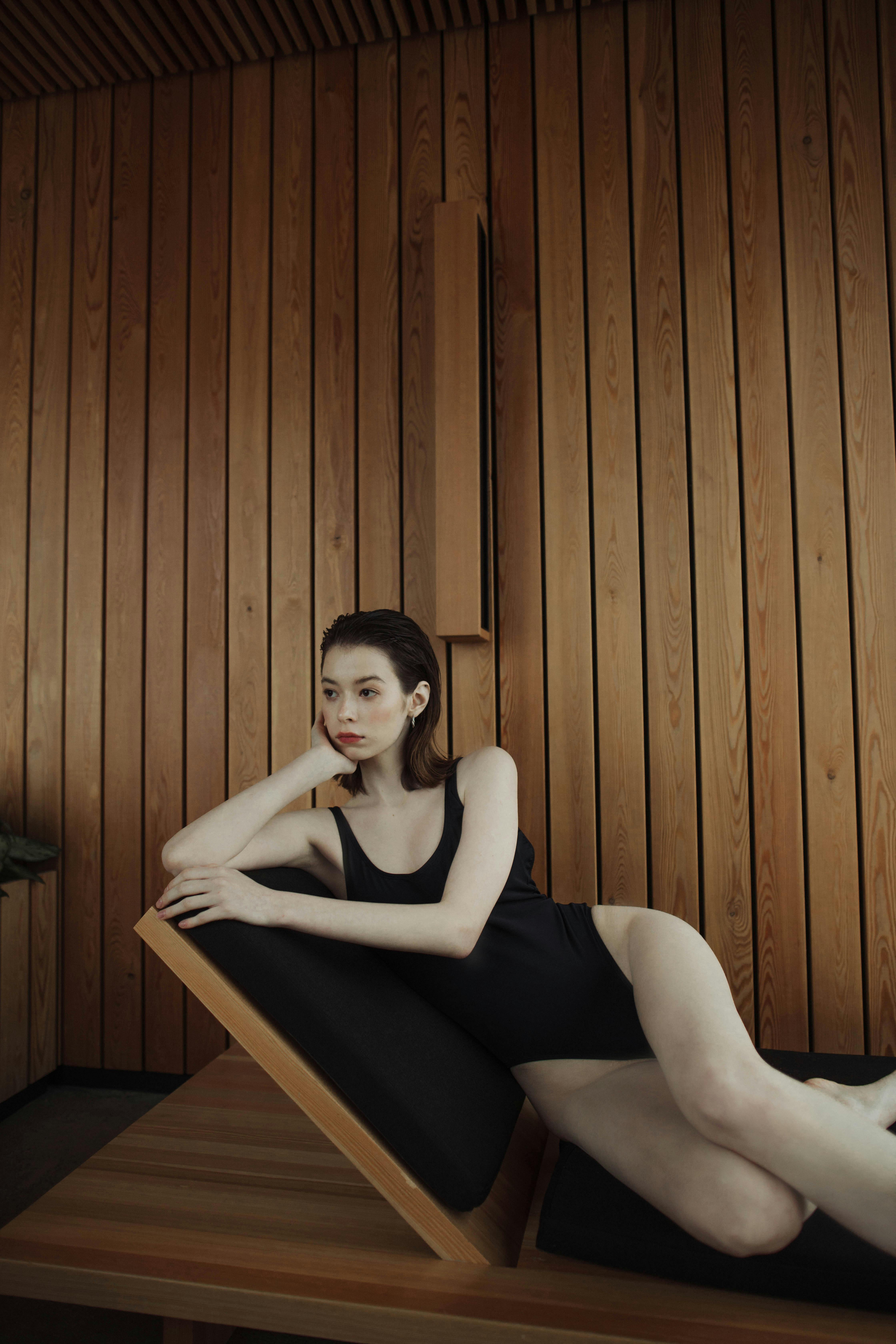 woman in black tank top and black leggings sitting on brown wooden bench