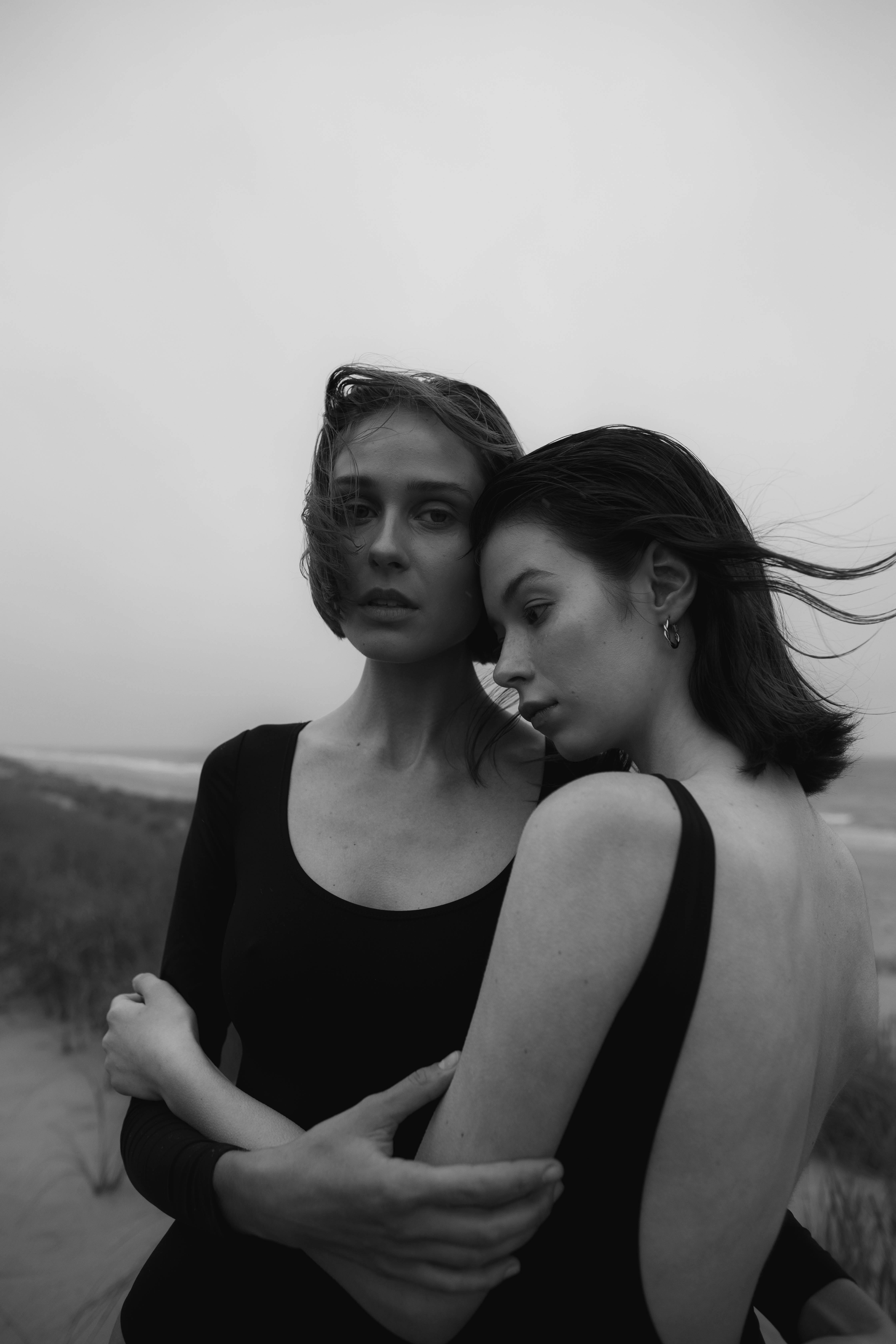 Grayscale Photo of Woman Kissing Womans Cheek