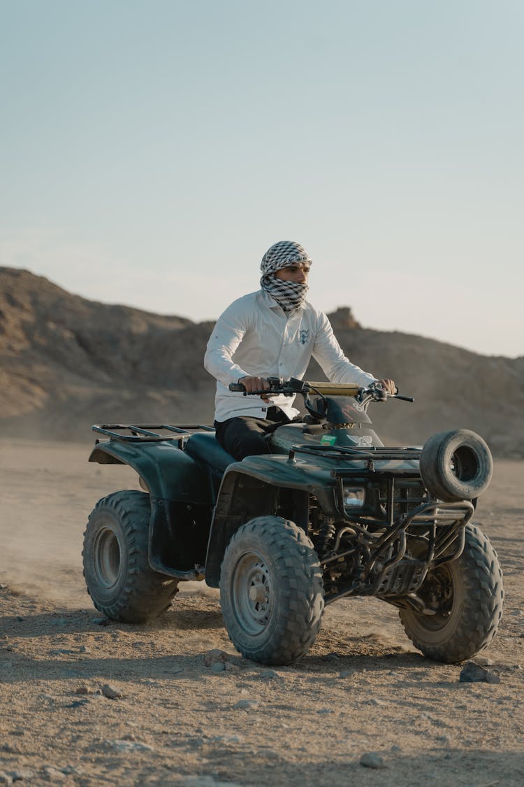 A Man Riding An ATV On The Desert