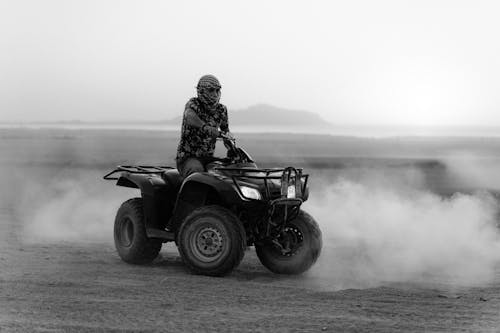 Grayscale Photo of Man Riding an All Terrain Vehicle